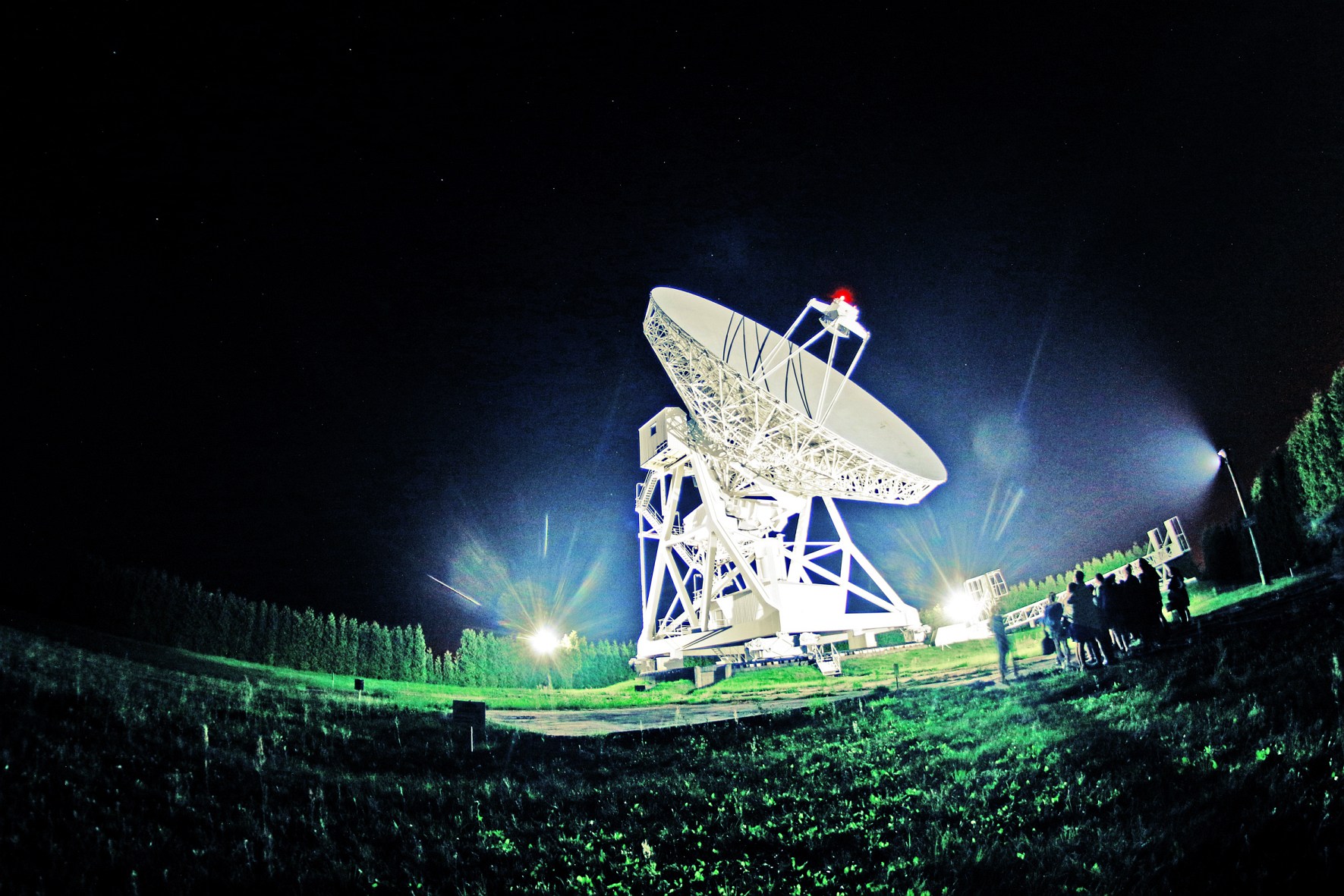 Radio telescope at the observatory in Piwnice by night.